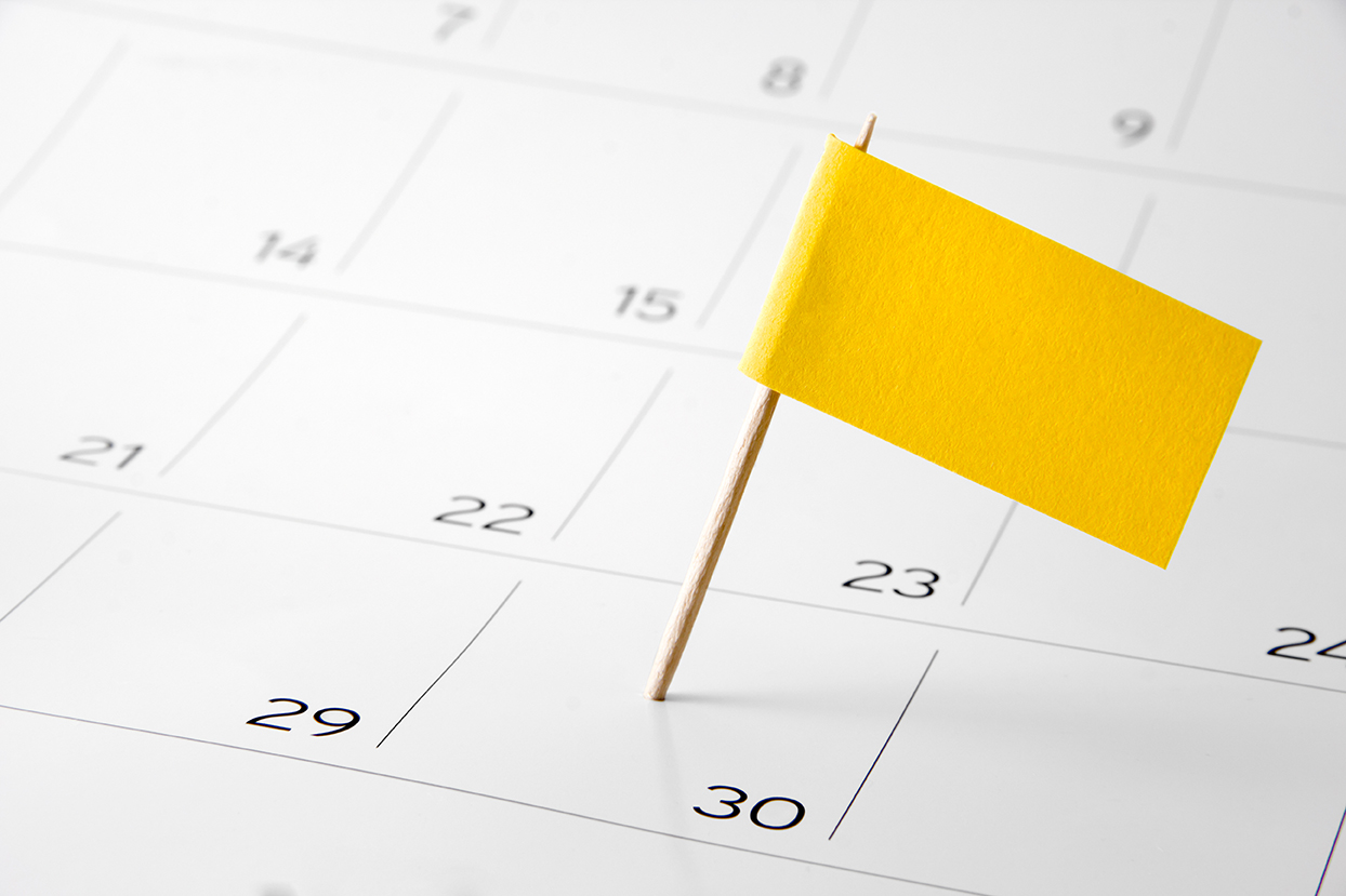 yellow pin flag placed on calendar